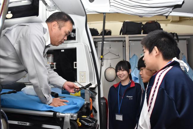 職場体験で救急車の中にある用具の説明を受ける中学生