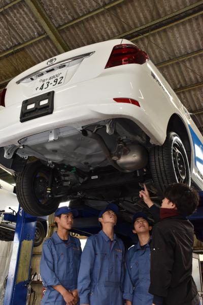 鴨川車検整備協業組合の職員から車の内部の説明を受ける中学生たち