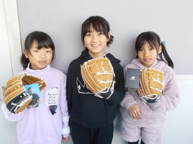 大谷選手から寄贈されたグローブをつけて記念撮影をする女子生徒3人