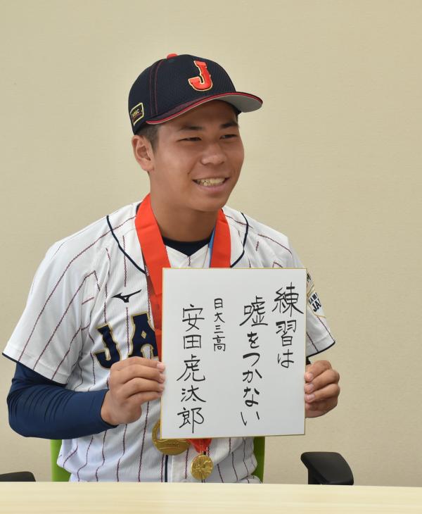 「練習は嘘をつかない」と書いた色紙を掲げる安田選手の写真