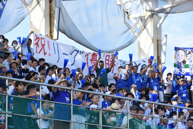 横断幕を掲げて祝福するサポーターの写真