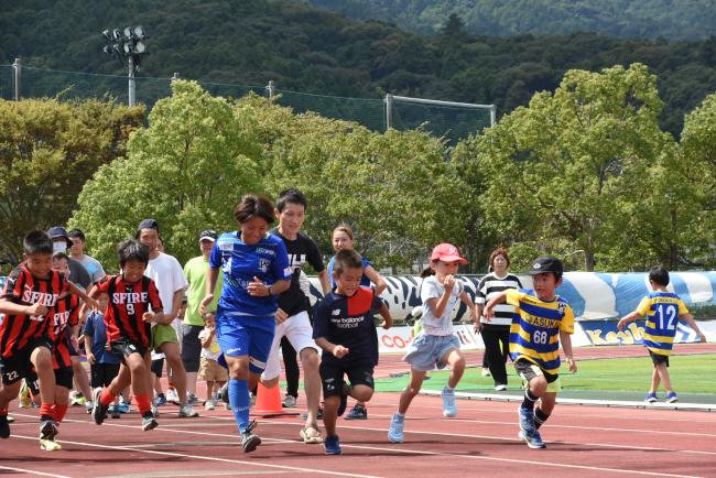参加者たちとトラックを走るオルカ鴨川FCの選手