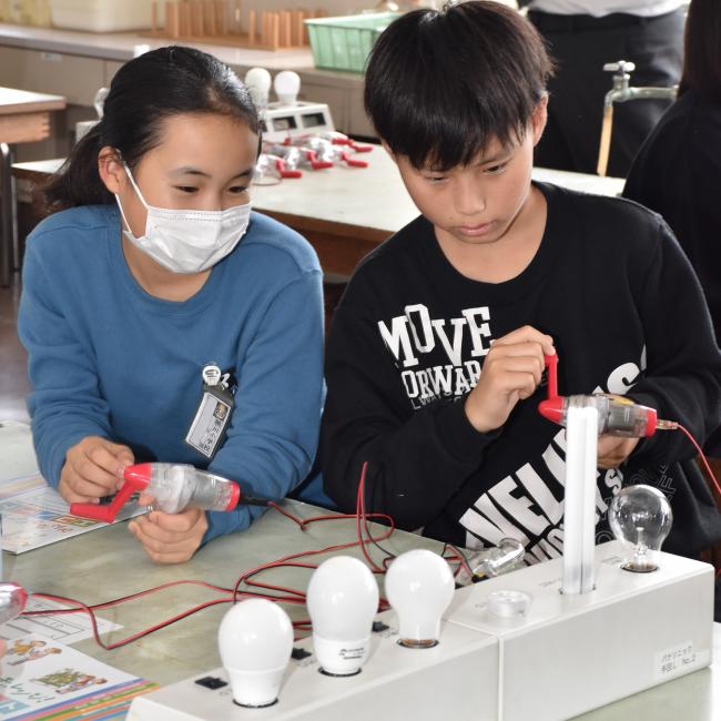 手回し発電機を用いて必要な電力の違いを学ぶ鴨川小学校の児童たち