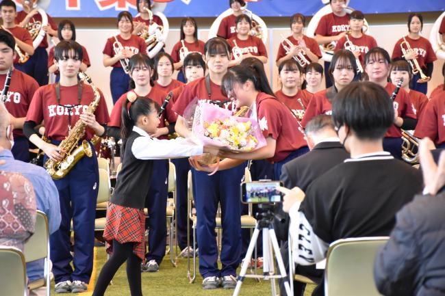 拓殖大学紅陵高等学校吹奏楽部の部長に花束を渡す鴨川市少年少女合唱団の団員