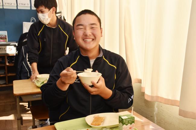 冬野菜のシチューを笑顔で食べる男子生徒