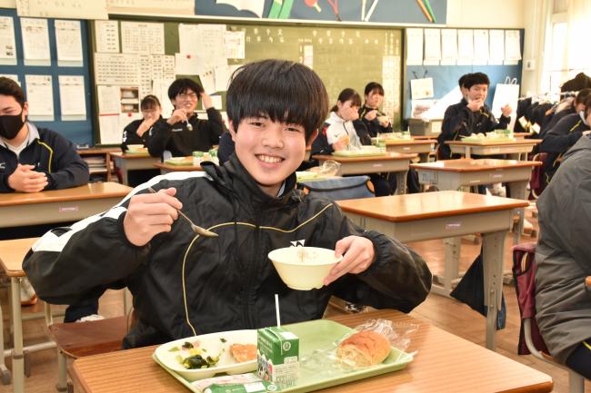 冬野菜のシチューをカメラに見せる男子生徒