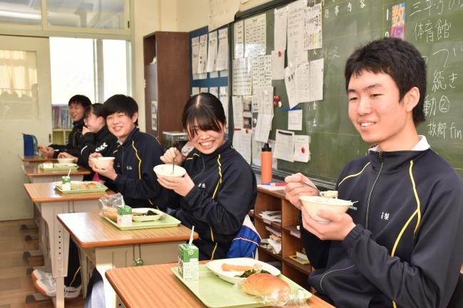 クライメイトらと笑顔で給食を食べる笹生さんの写真