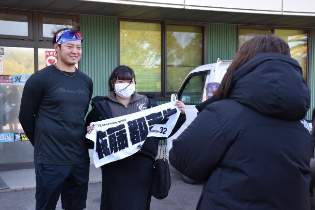 佐藤選手のタオルを持つファンと写真を撮る佐藤選手