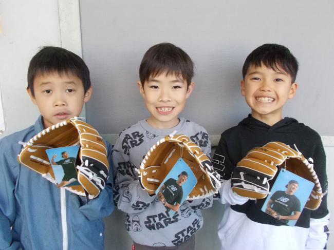 大谷選手から寄贈されたグローブをつけて記念写真を撮る男子生徒3人