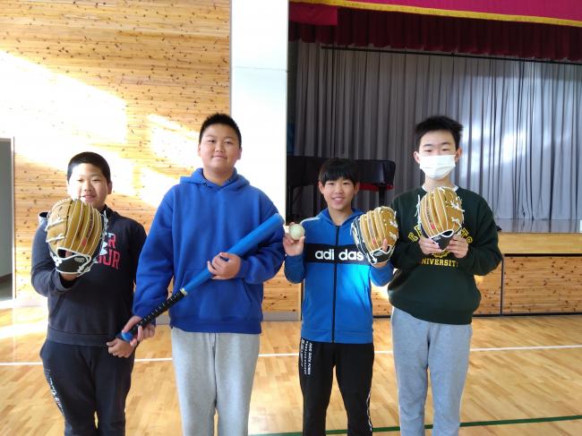 大谷選手から寄贈されたグローブをつけて記念写真を撮る男子生徒4人