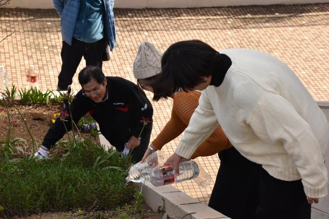 花壇の花に水やりをする観光客の写真