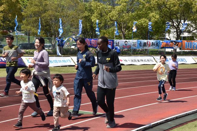 親子かけっこ教室の参加者とトラックを走る日本航空学園女子サッカー部の生徒