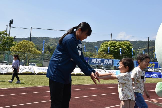 参加者の子どもとハイタッチする日本航空学園女子サッカー部の生徒