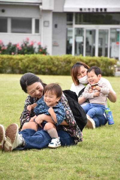 子どもを膝の上にのせて体操をする親子