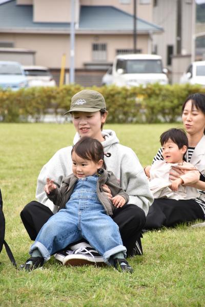 子どもを膝の上にのせて笑顔で体操をする親子