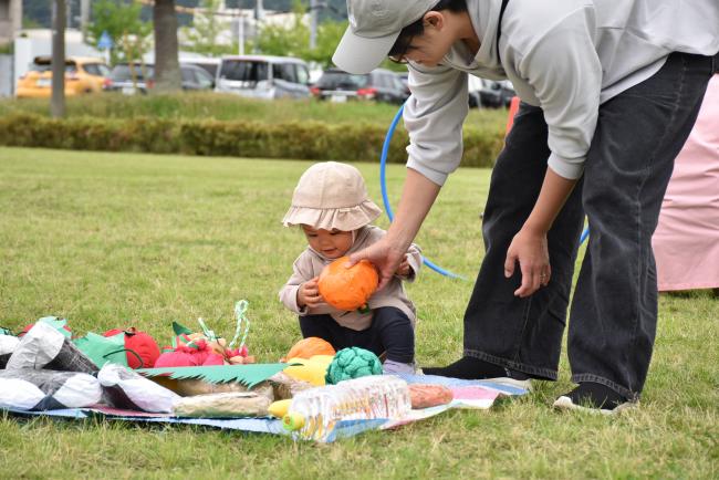 お弁当のおかずを模したおもちゃを選ぶ子供と保護者