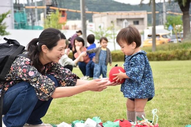 お弁当のおかずを模したおもちゃを子どもに渡す親