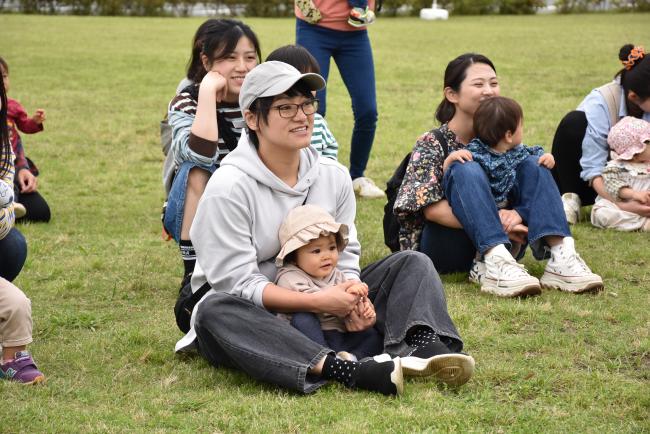 子どもを膝の上にのせて読み聞かせを聞く親