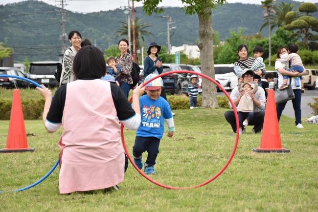 フラフープをくぐる子どもとそれを見守る保護者