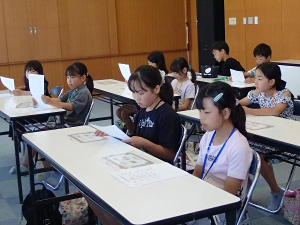 資料を見ながら図書館での仕事の内容を聞く児童