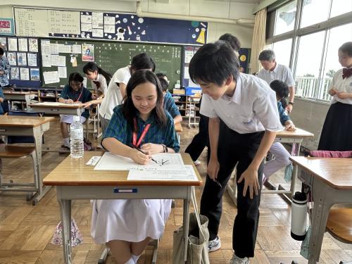 筆ペンの使い方を優しく教える9年生男子