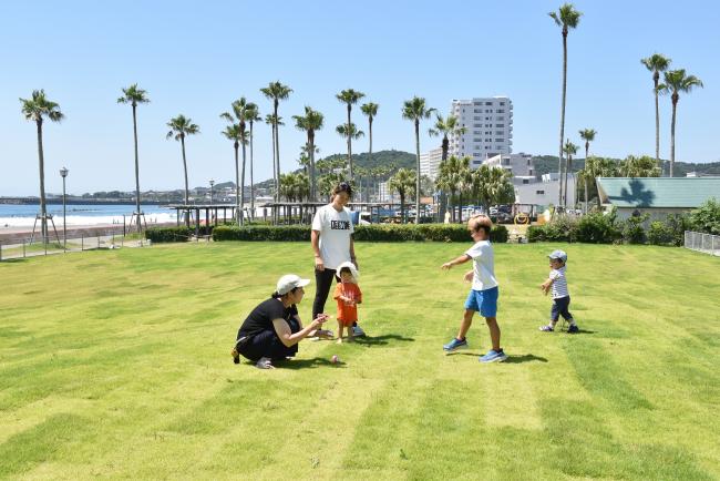芝生広場で遊んでいる親子たちの写真