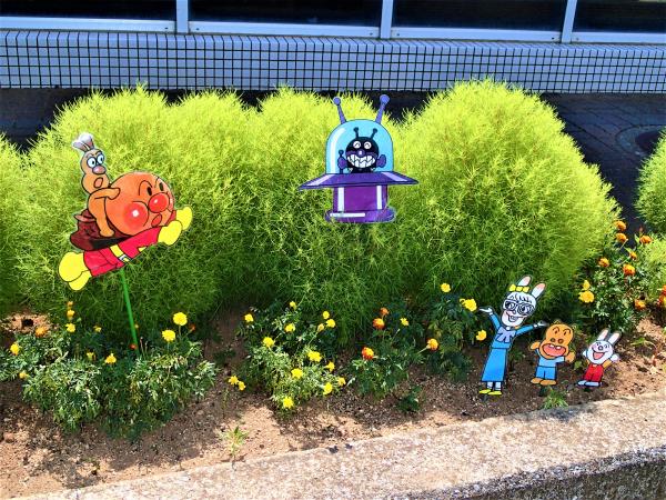 花壇の上を飛ぶアンパンマンとバイキンマン
