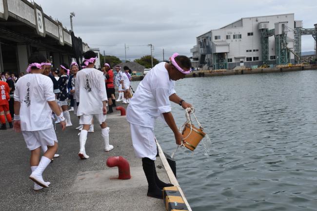 鴨川漁港で海水を汲む大浦八雲神社の団長の写真