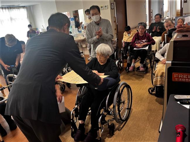 市長からお祝い状を受け取られる大塚シマエさんと施設の皆さん