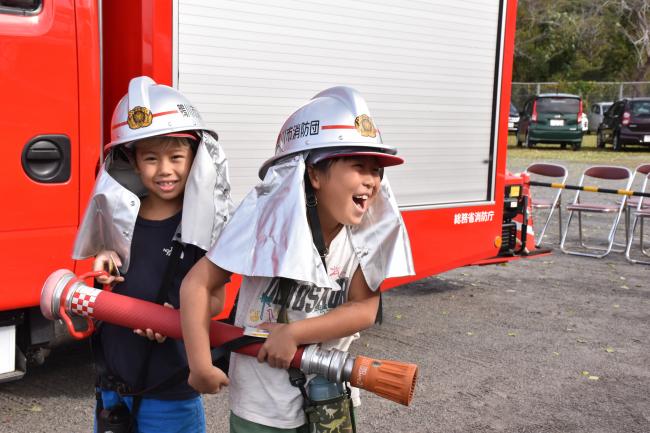 消火ホースをもって笑う児童