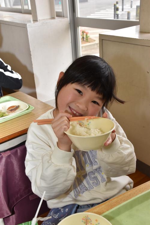 寄贈の新米長狭米をもって笑顔の江見小学校2年生の女の子