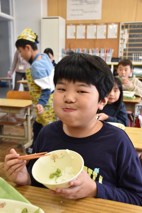 寄贈の新米長狭米と鴨川七里を口いっぱいにいれた江見小学校2年生の男の子の写真