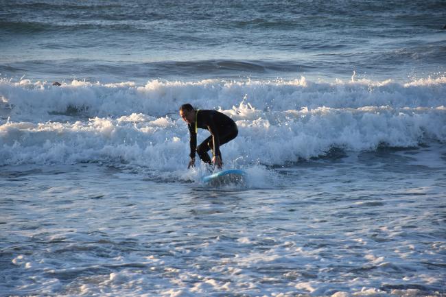 海に出てボードの上に立とうとする市長の写真