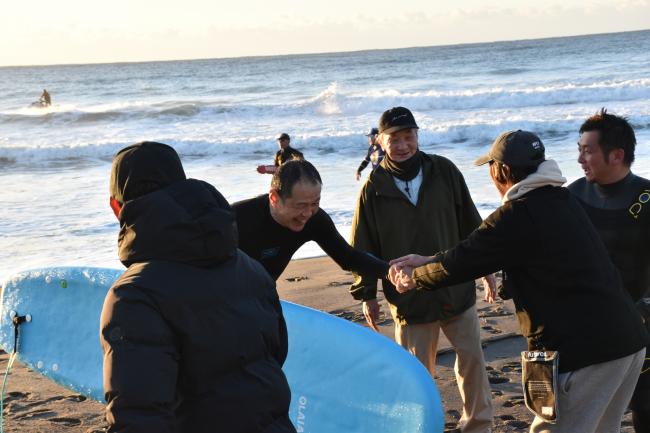 波打ち際に集まった関係者や観客と握手をする市長の写真