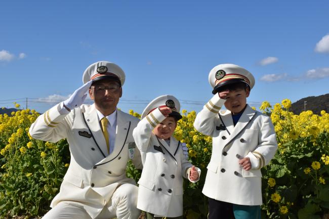 ＪＲ安房鴨川駅の駅長と車掌服を着て記念撮影をする子どもの写真