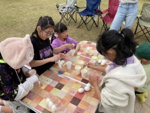 5人の子どもが卵の殻に色をつけている様子