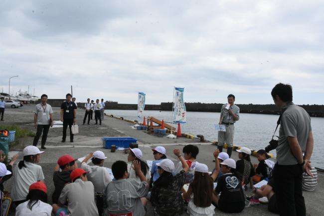 県の職員から説明を受けている児童の写真