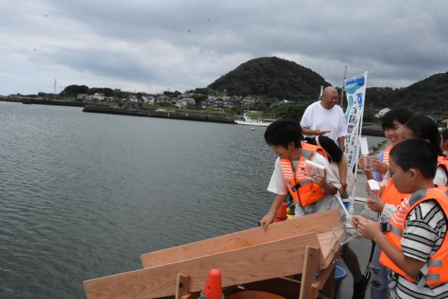 マダイの稚魚を放流する児童の写真