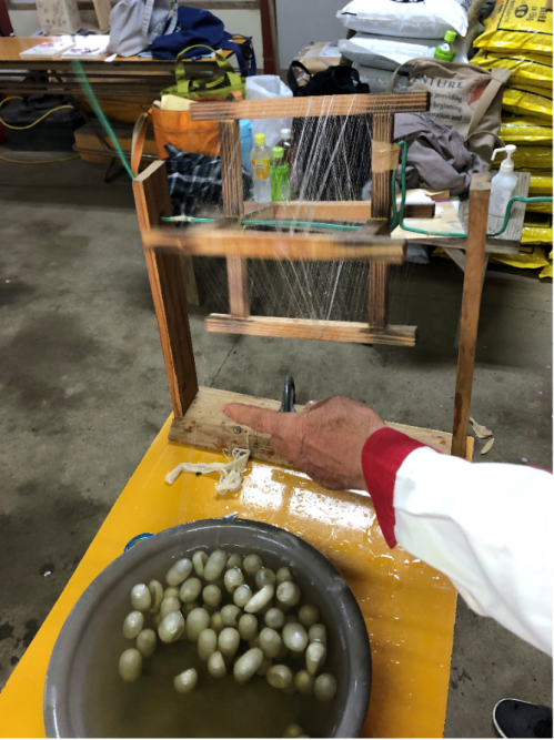 繭糸をランプシェードの木枠へ巻き付ける作業
