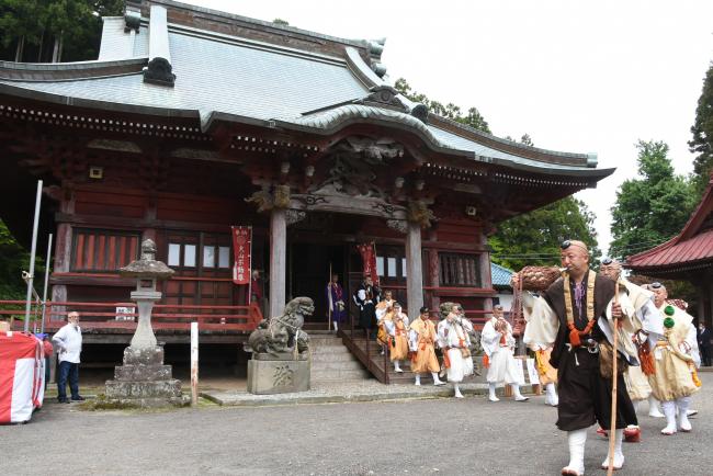 ほら貝を吹かせながら儀式の場へ向かう山伏姿の修験者